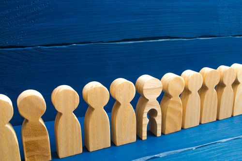 Holzfiguren in einer Reihe, eine hat ein ausgeschnittenes Kind